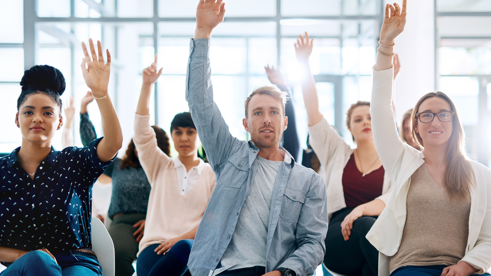 A group of people raising their hands in an office during a quick FAQ session about fasting.